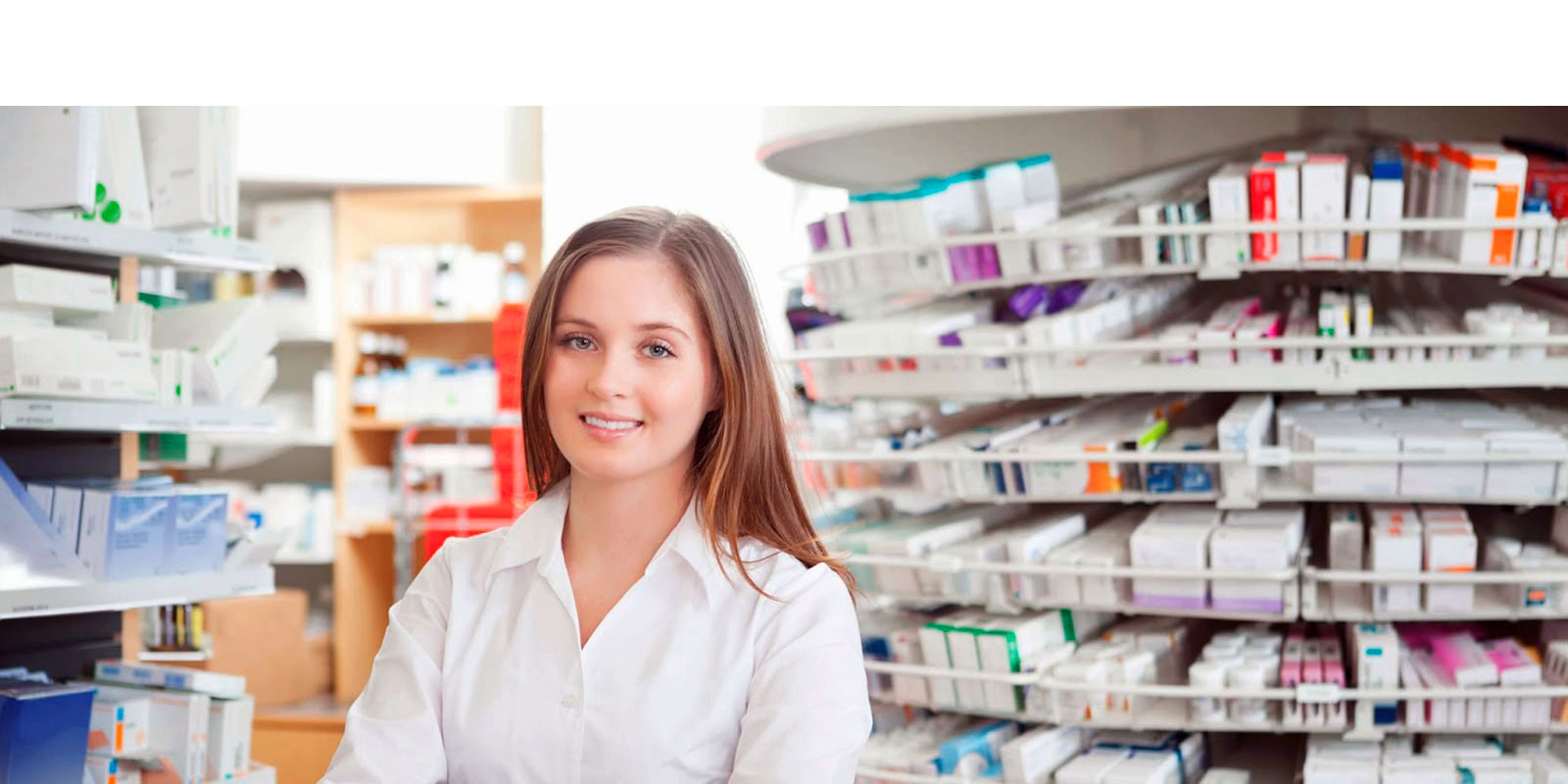 A woman sitting in front of shelves filled with medicine.