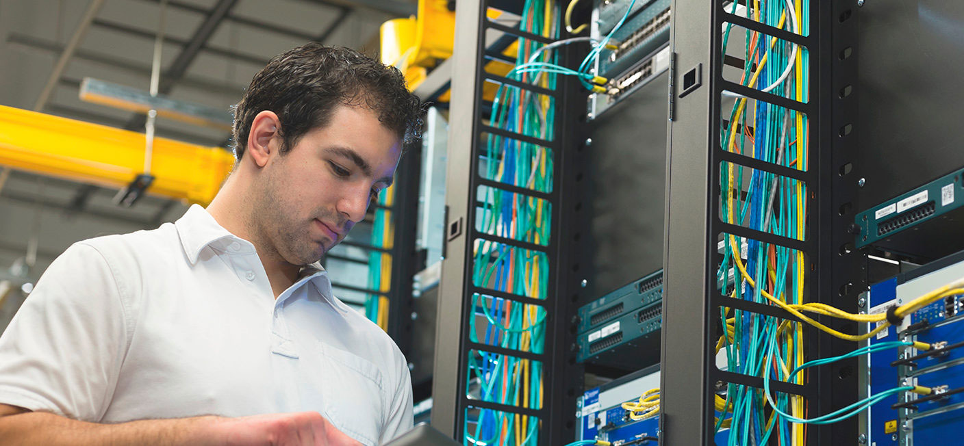 A man looking at the wires in his server room.