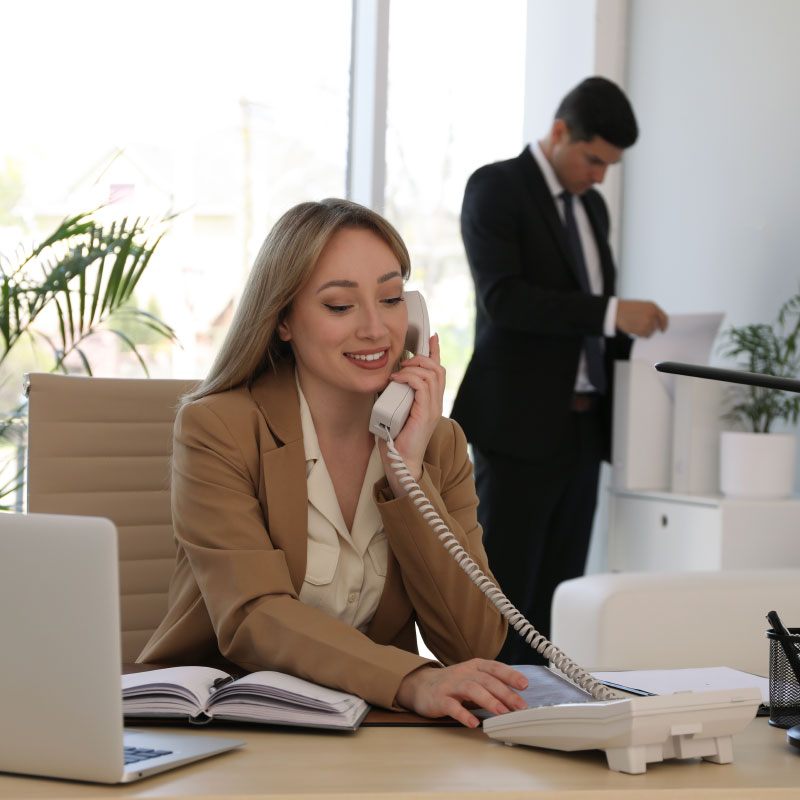 A woman sitting at her desk talking on the phone.