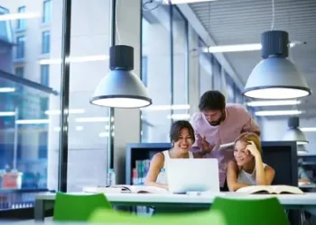 two girls and a boy looking at the compter on the table